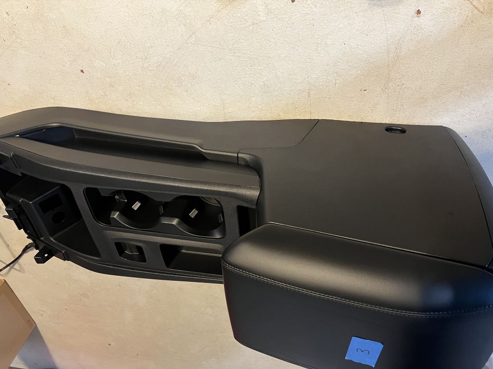Vehicle center console with two cup holders and a padded armrest