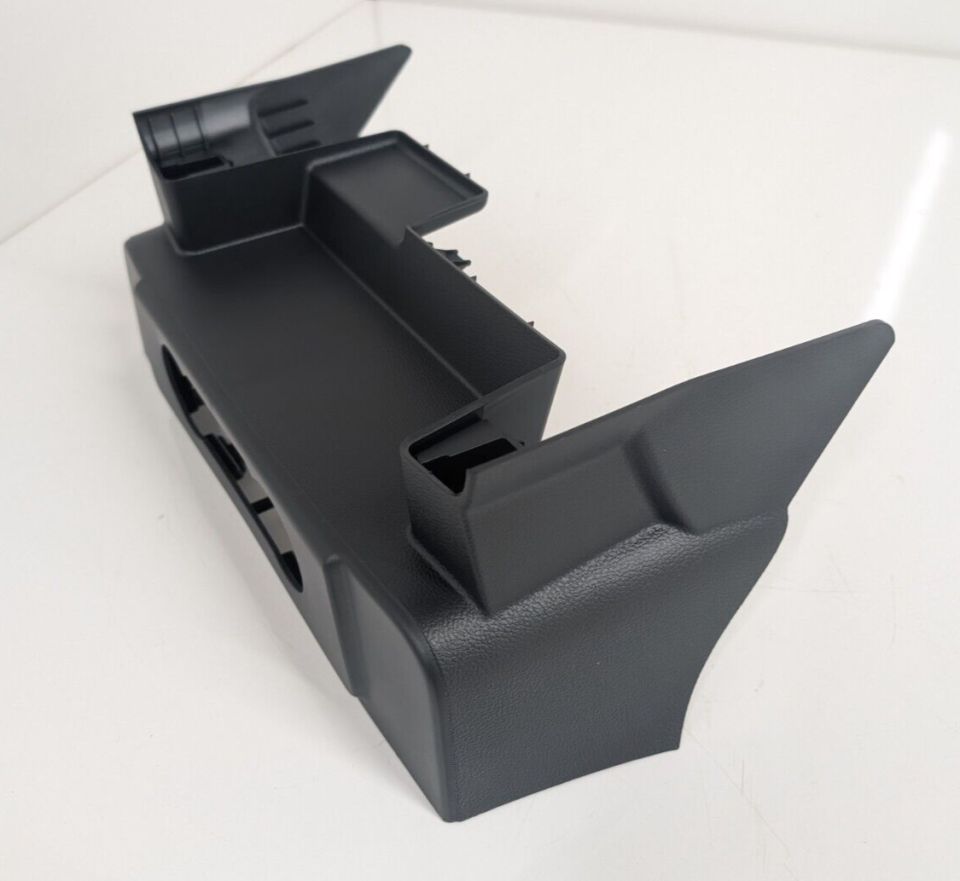 Black molded plastic interior trim panel or console piece on white background