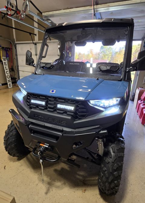 2025 Polaris RANGER - Front view of a blue UTV, a winch and multiple LED light bars on the grille.