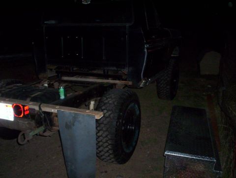 1978 Ford Bronco - The rear section of a black truck chassis is visible, with large tires and a fuel tank.