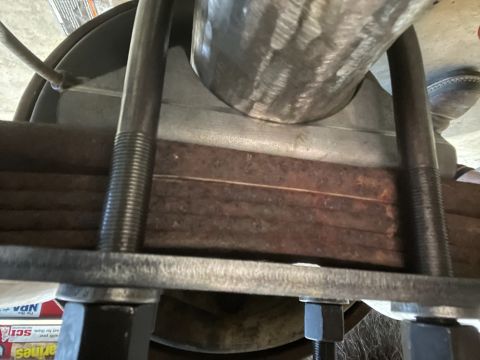 1979 Ford Bronco - Close-up of a vehicle's leaf spring and U-bolt assembly, likely undergoing maintenance.