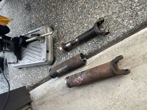 1979 Ford Bronco - Parts of a driveshaft lie on the ground next to a chop saw, ready for modification.