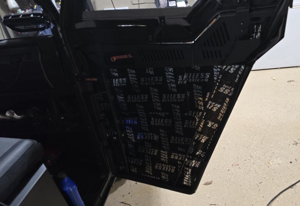 Interior of a vehicle door with sound deadening material applied to the panel