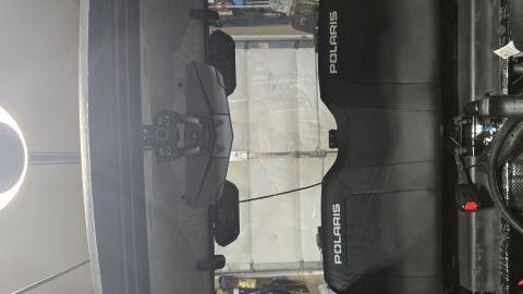 2025 Polaris RANGER - A black Polaris side-by-side vehicle is shown parked inside a garage with the doors up.