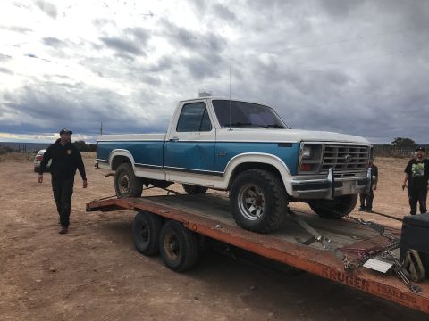 1994 Ford Bronco - A white and blue pickup truck is being loaded onto a flatbed trailer.