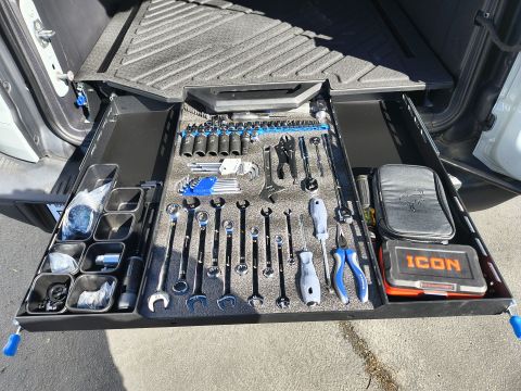 2023 Ford Bronco - A vehicle's cargo drawer is opened to reveal a neatly organized collection of tools, including various wrenches and sockets.
