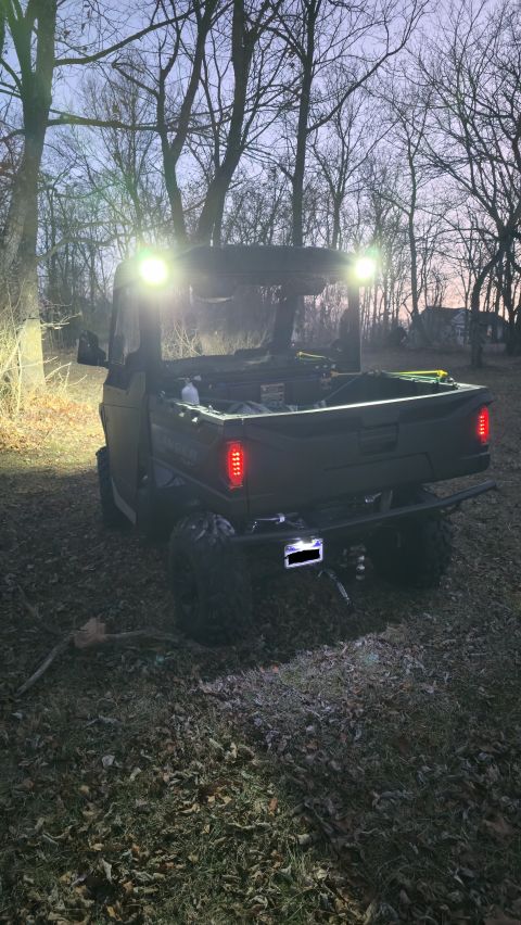 2025 Polaris RANGER - UTV parked outdoors at dusk, illuminated by its own lights.