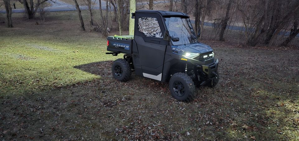 Polaris RANGER side-by-side utility vehicle parked on grassy ground with trees in background