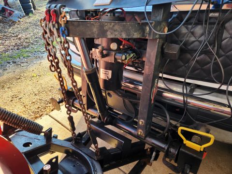 1997 Ford F-250 - Close-up view of a plow mount system, including chains and hydraulic components, attached to the front of a vehicle.