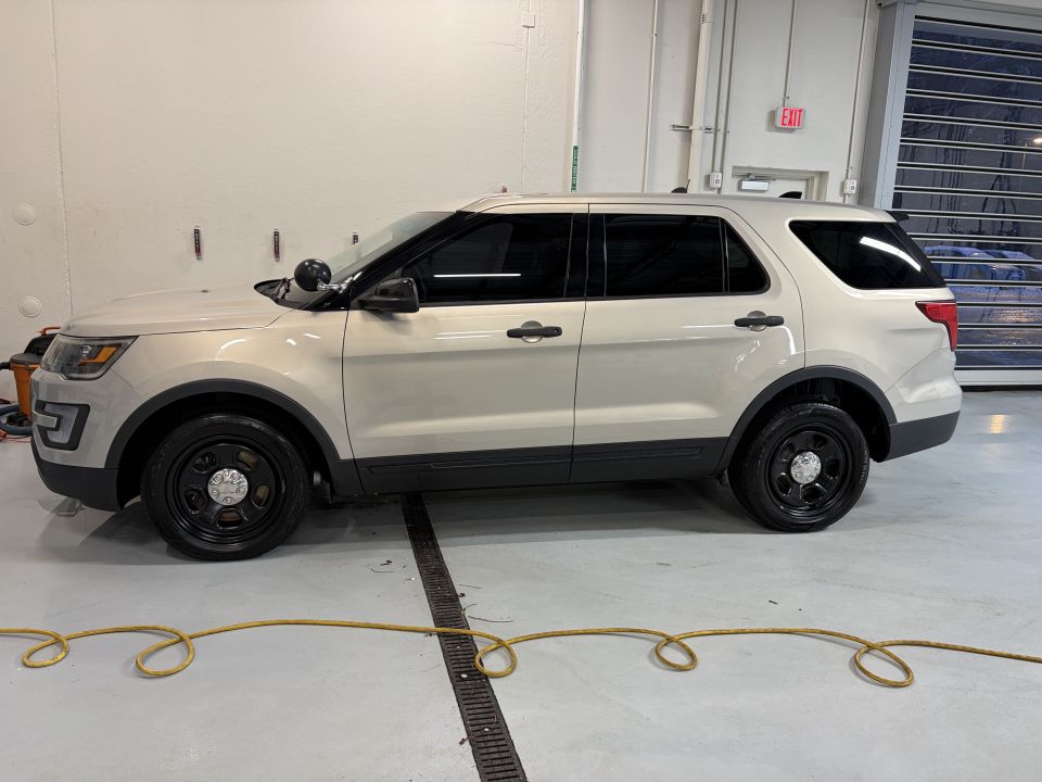 Side view of a tan police SUV with black steel wheels and a light bar on the roof