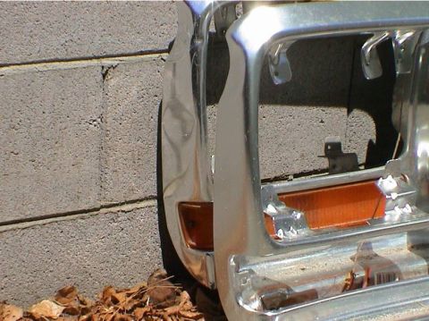 1979 Ford Bronco - Close-up view of a vehicle's chrome grille and orange turn signal assembly, leaning against a textured brick wall.