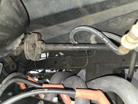 1974 Ford Bronco - Close-up view of the steering linkage and exhaust manifold, with readable text on a hose.