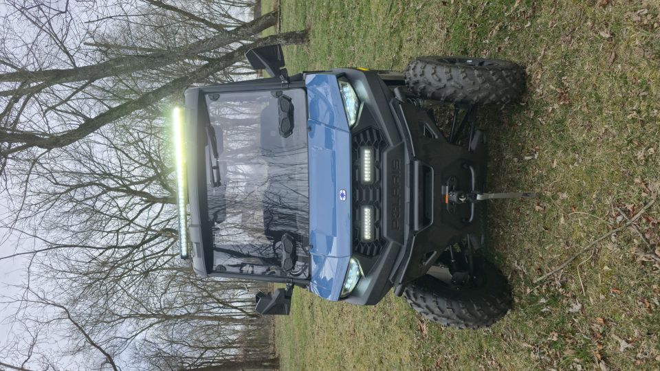 Blue UTV with front LED light bars and a roof-mounted light bar