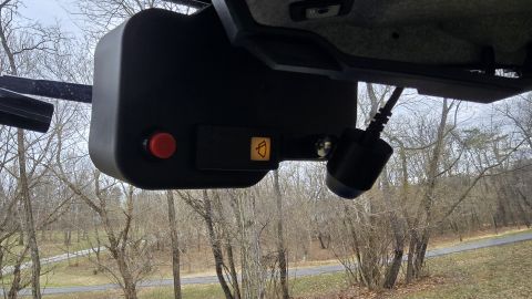 2025 Polaris RANGER - An aftermarket accessory with a camera is mounted inside a vehicle, with trees visible outside.