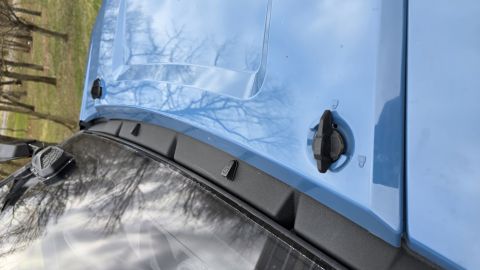 2025 Polaris RANGER - Close-up view of the hood and windshield area of a blue vehicle, showing latches and a wiper assembly.