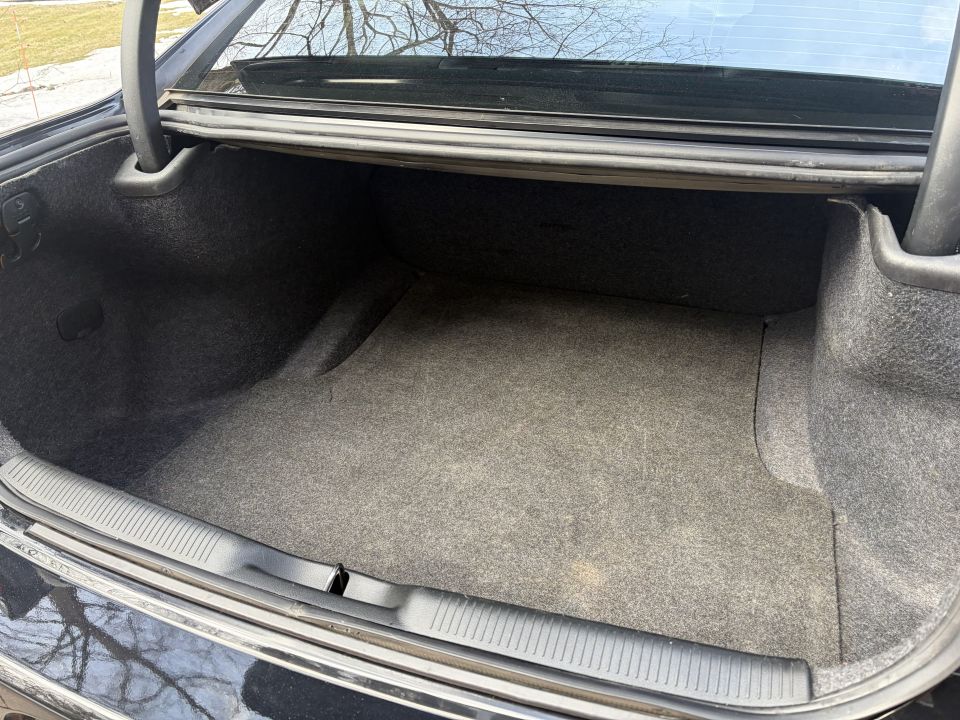 Empty car trunk with gray carpet lining. Trunk lid is open