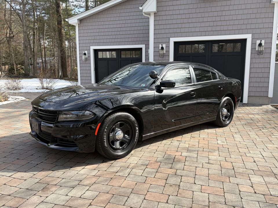Black police sedan parked on a paver driveway in front of a garage