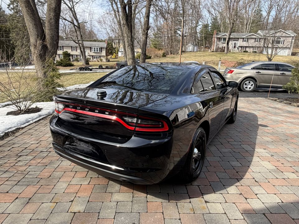 Black Dodge Charger rear quarter view, parked on a paver driveway