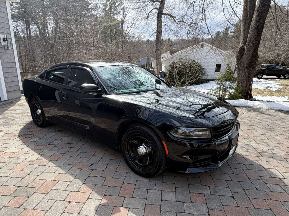 Black police car parked on a paver driveway, front 3/4 view
