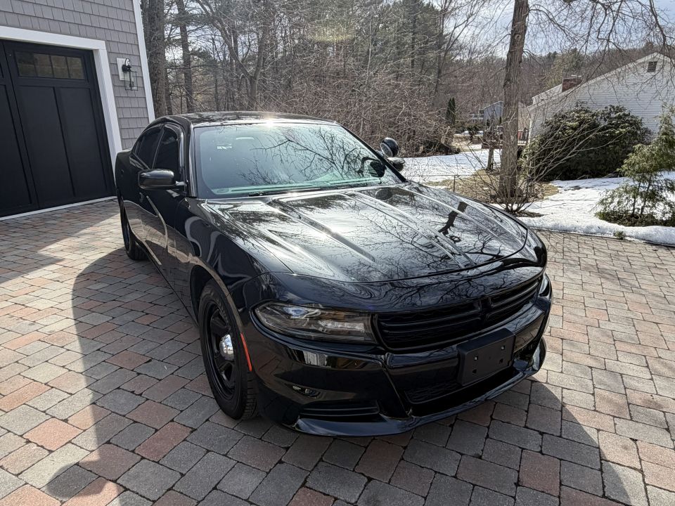 Black Dodge Charger police car parked on a paved driveway