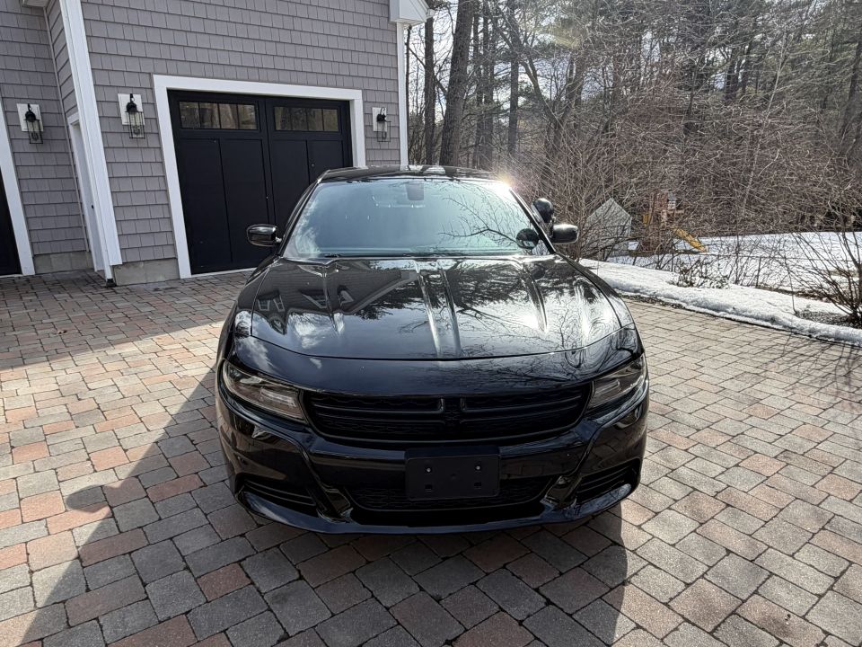 Black Dodge Charger parked in driveway in front of garage