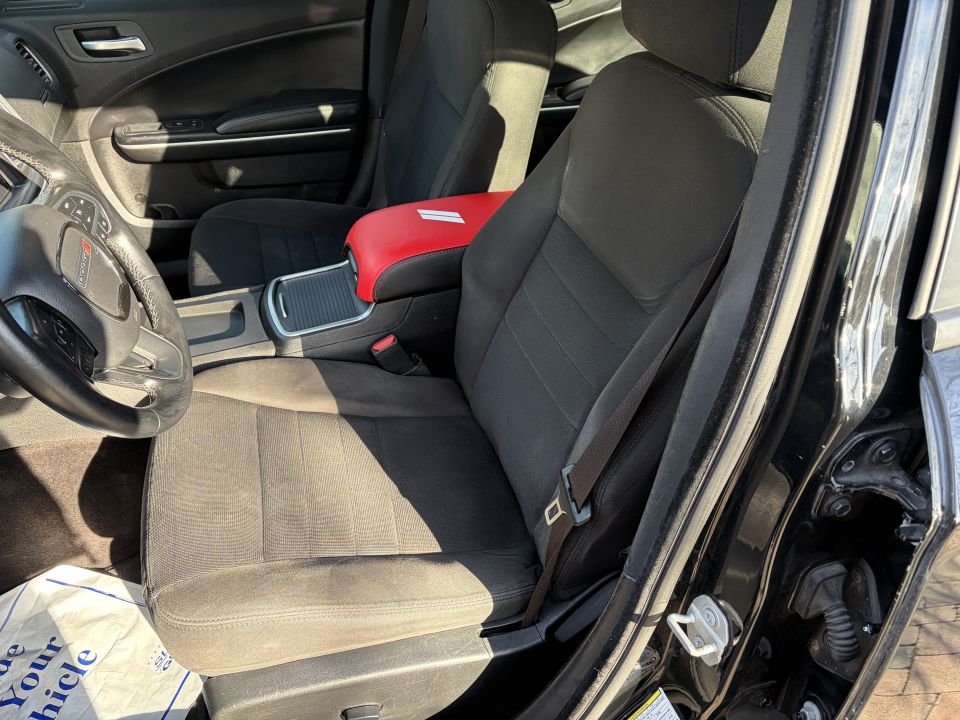 Car interior showing front passenger seat, dashboard, steering wheel, and center console with red armrest