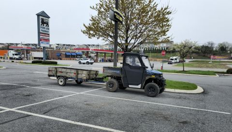 2025 Polaris RANGER - A UTV is parked in a lot, hitched to a trailer, with a Food Lion sign in the background.