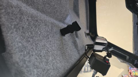 2025 Polaris RANGER - Close-up view of the interior lining and a clip inside a vehicle cabin, with a side mirror and control panel visible.
