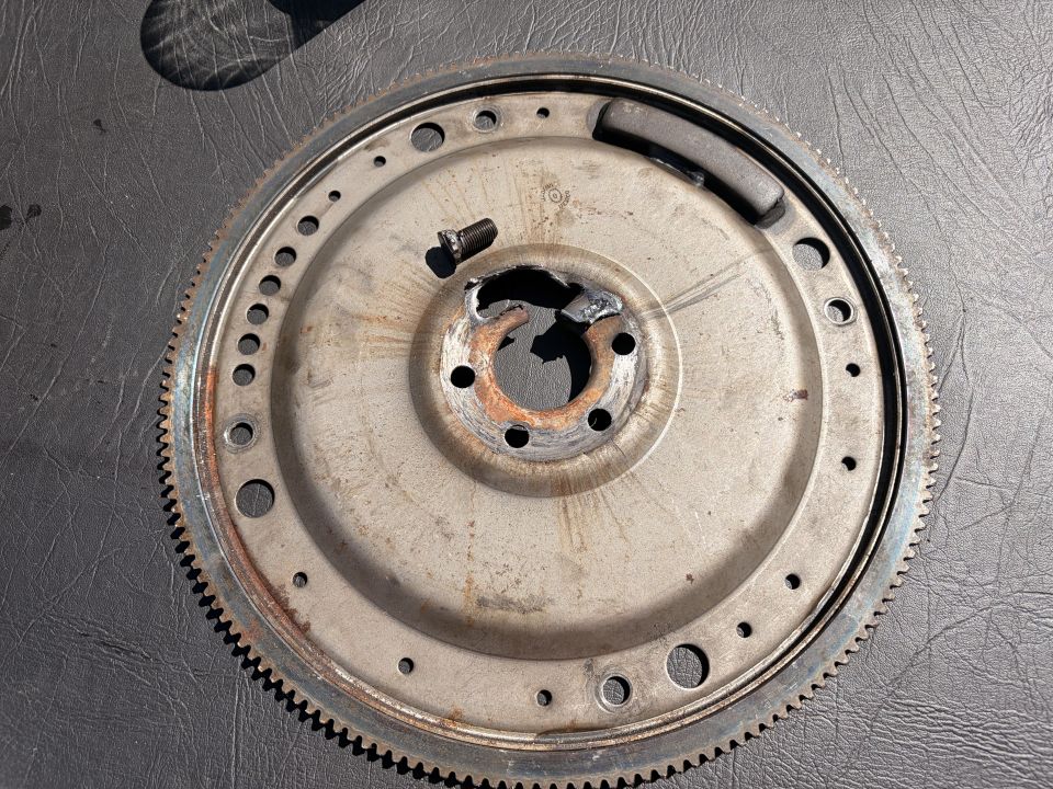 Flywheel with a damaged center bore and a bolt inserted into one of the mounting holes