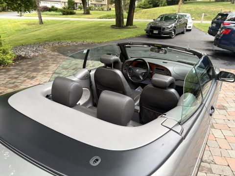 2001 Ford Crown Victoria - Top-down convertible with its soft top lowered, viewed over the rear deck toward gray leather seats, headrests and a Saab-badged steering w…