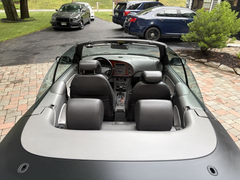 2001 Ford Crown Victoria - Rear three-quarter interior view of a gray convertible with the top down, showing two rows of black leather seats, wood-trimmed dash and ce…