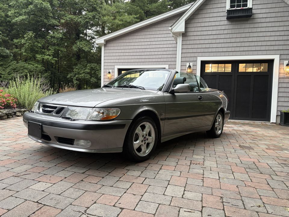 Gray Saab 9-3 convertible front three-quarter view, top down, on brick driveway