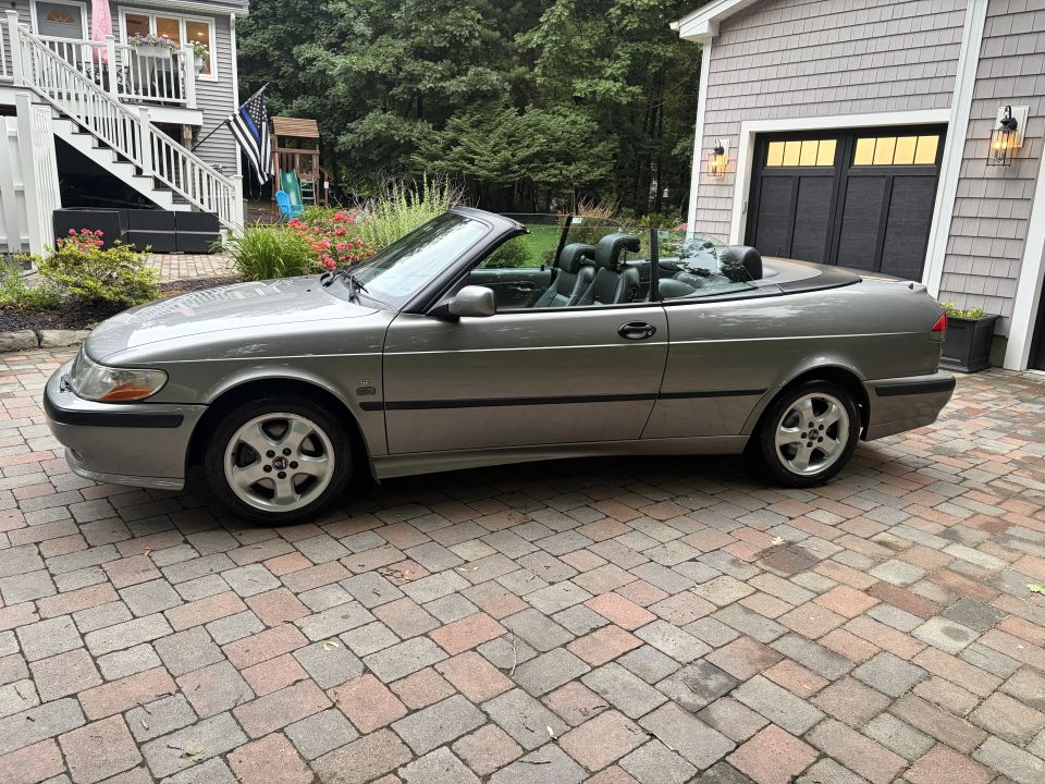 Side profile of a gray Saab convertible with top down on a paver driveway
