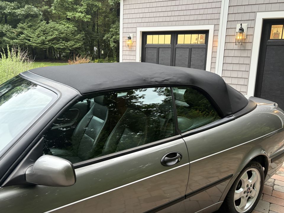 Silver-gray Saab convertible with black soft top up, side view