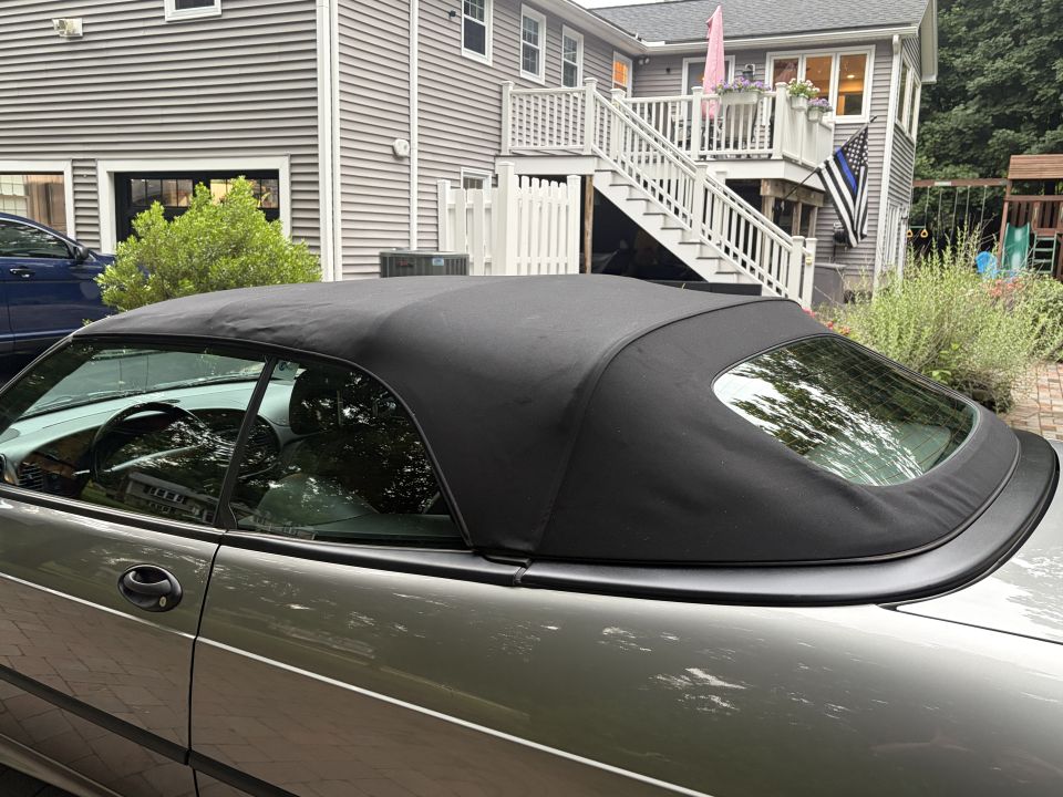 Gray convertible with black soft top raised, side rear view