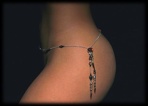1984 Ford Bronco - Body jewelry with beads and charms is worn around the waist against a dark background.