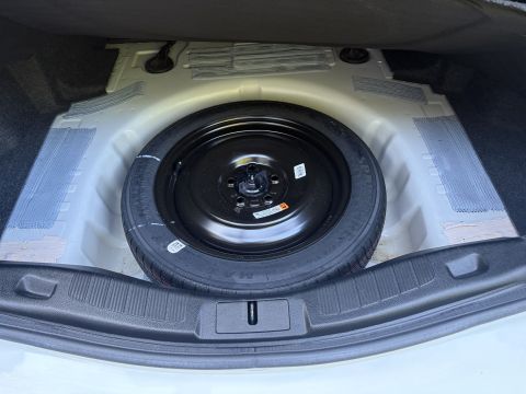 2001 Ford Crown Victoria - Open trunk showing a compact black steel spare wheel with a Maxxis SpaceMiser tire seated in the spare well, with warning labels on the tir…