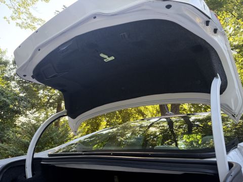 2001 Ford Crown Victoria - View of the open trunk lid of a white sedan from inside the trunk, showing the carpeted underside of the lid and the rear glass and rooflin…