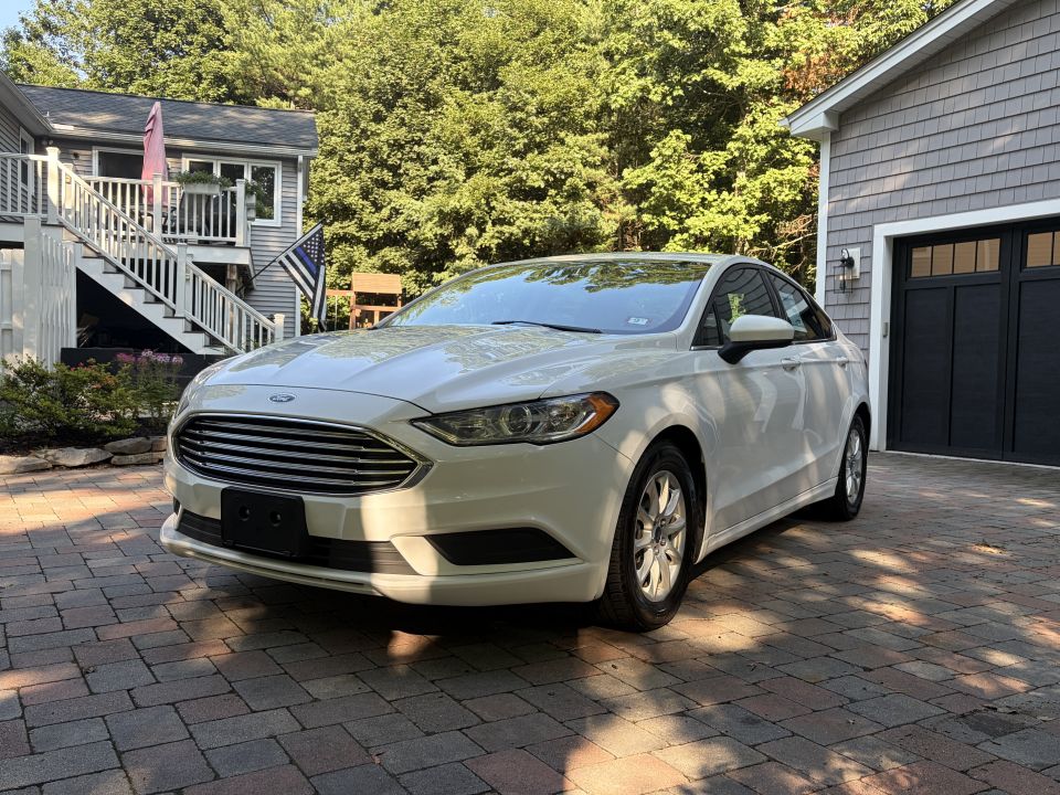 White Ford Fusion sedan, driver-side 3/4 front view on pavers