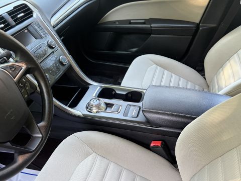 2001 Ford Crown Victoria - Interior of a Ford Fusion showing the center console with rotary gear-shift dial, cupholders and armrest, flanked by tan cloth front seats…