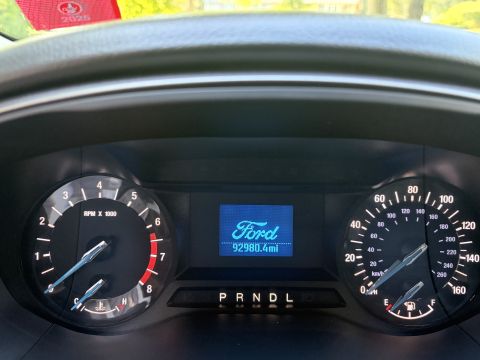 2001 Ford Crown Victoria - Ford instrument cluster with analog tachometer and speedometer flanking a blue center display reading 'Ford' and 92980.4 miles, PRNDL gear…