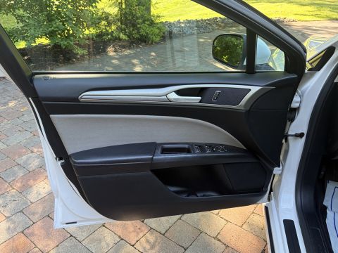 2001 Ford Crown Victoria - Interior view of an open driver's door on a white sedan, showing the two-tone black-and-gray door panel with a chrome accent strip, cloth i…