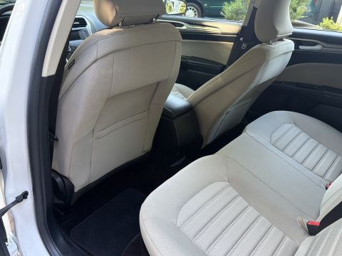 2001 Ford Crown Victoria - Rear seats of a Ford Fusion in tan/beige cloth upholstery, viewed through the open rear door with the front seatbacks in the foreground.