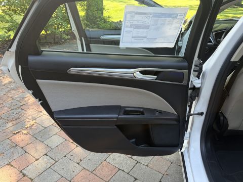 2001 Ford Crown Victoria - Interior of an open rear door on a white Ford, showing the two-tone black and tan door panel with a chrome accent strip. A Ford window Monr…