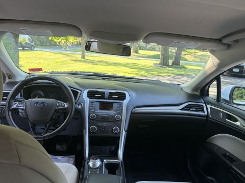 2001 Ford Crown Victoria - Interior dashboard view of a Ford sedan with tan cloth seats, Ford-badged steering wheel, center touchscreen stack, and rotary shift dial o…