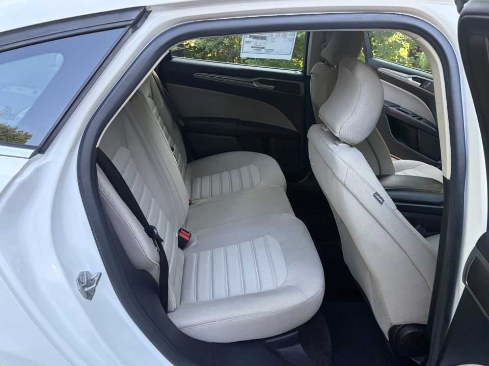 White sedan rear seats in tan cloth, window sticker on glass