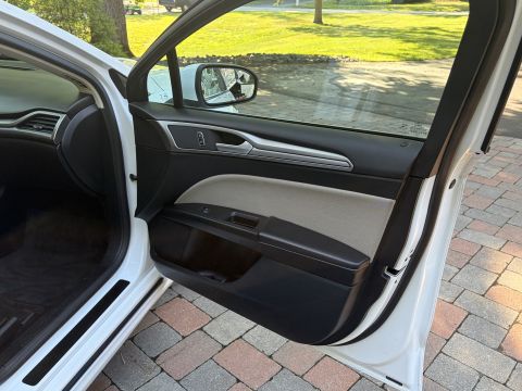 2001 Ford Crown Victoria - Open front door of a white sedan showing the black and light-stone door panel, side mirror and window switches. A brick paver driveway and…
