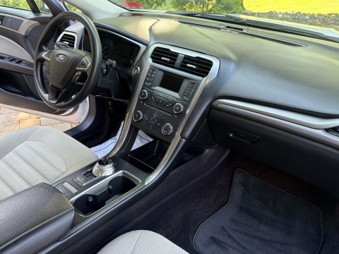 2001 Ford Crown Victoria - Passenger-side interior of a Ford sedan showing the dashboard, center console with rotary shifter, tan cloth seats, and black floor mats.