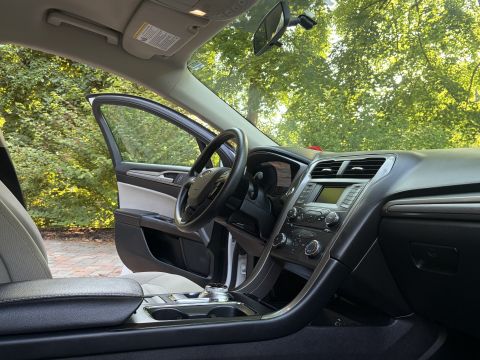 2001 Ford Crown Victoria - Passenger-side interior view across a black dashboard and steering wheel bearing a Ford oval, with light gray leather seats and a center st…