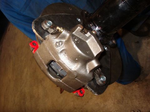 1985 Ford Bronco - A close-up view shows a newly installed brake caliper assembly, painted brown with red accents, mounted to a vehicle's axle. The caliper is…